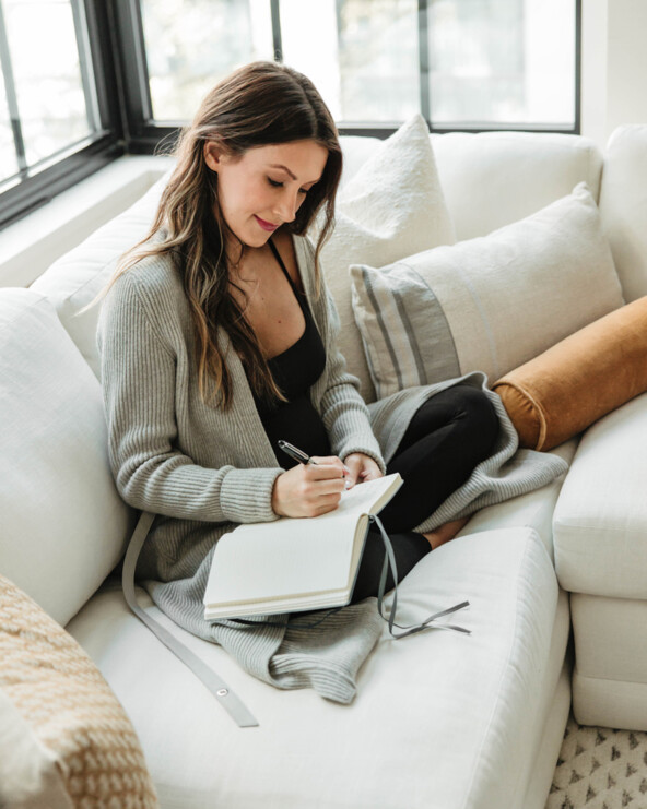 Woman journaling on couch.