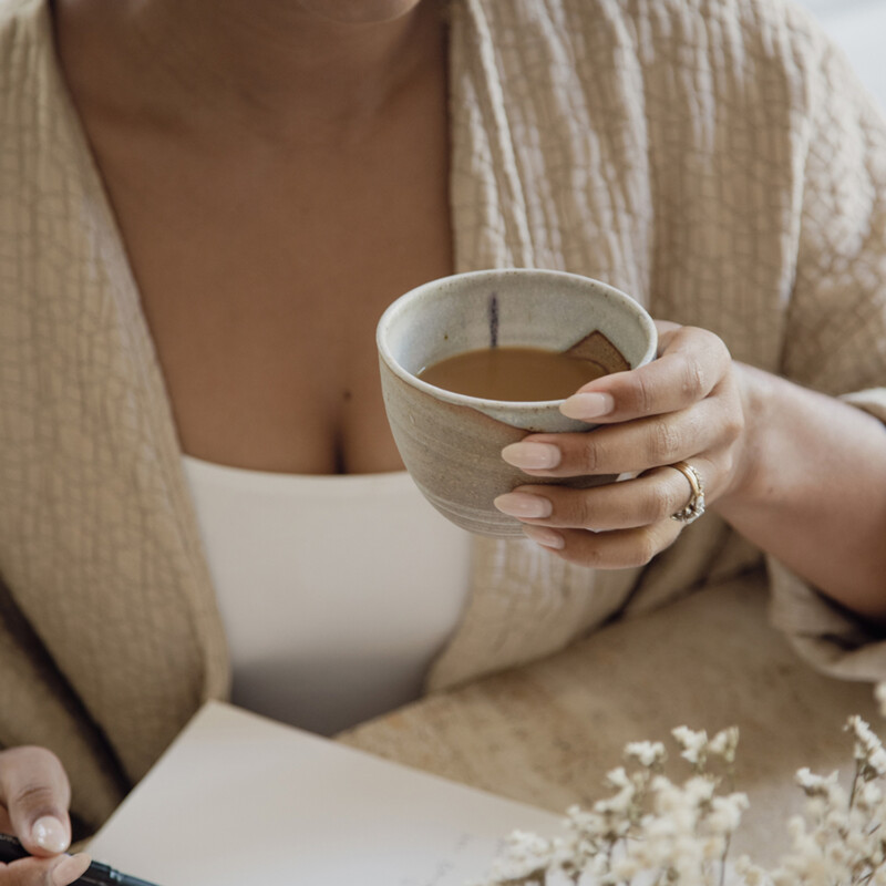 Woman drinking coffee journaling.