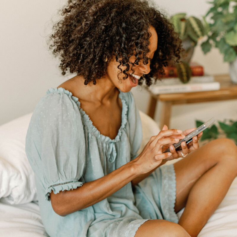 Woman using phone in bed.